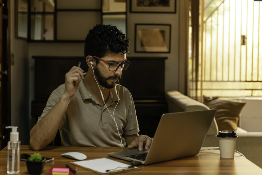 Man sits in home study working on laptop