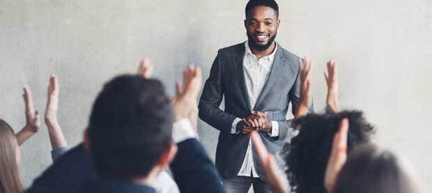 man-standing-in-front-of-a-group-who-have-their-hands-raised-clapping