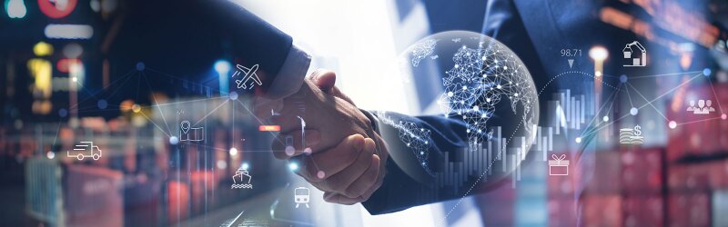 Two business people shaking hands with global trade, shipping, and finance icons overlayed, symbolizing international business.