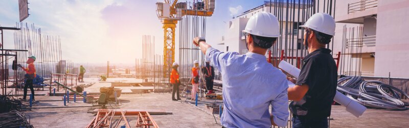 Smart civil architect engineer inspecting and working outdoors structure building site with blueprints.