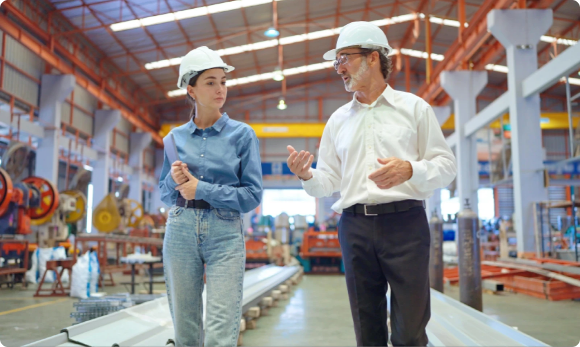 two people walking through a building with large machines