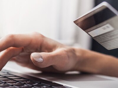 Consumer holding a credit card and using a laptop to purchase online.