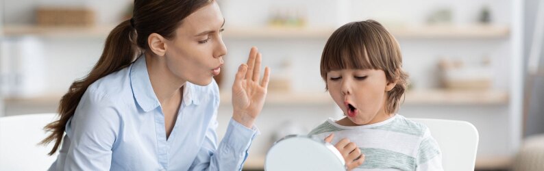 Little boy pronouncing sound O looking at mirror, professional woman therapist teaching kid right pronunciation.