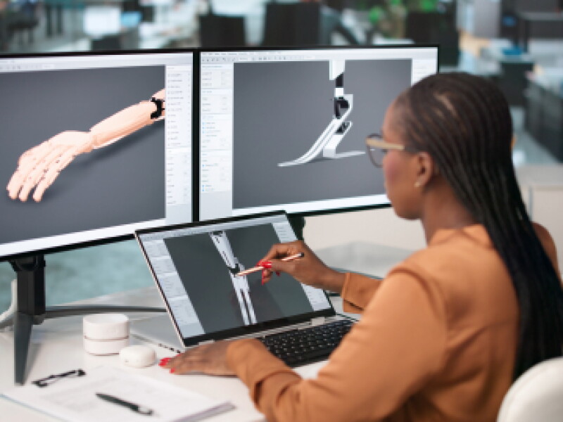 A female CWRU biomedical student reviews prosthetic wireframes on a computer screen.