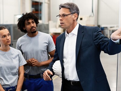 Manager explaining new strategy plans to group of employees in a factory