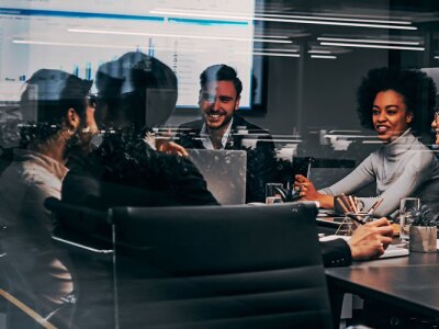 Group of business professionals gathered around meeting table for presentation.