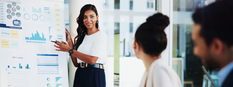 An executive uses data visualization to present information to colleagues in a meeting.