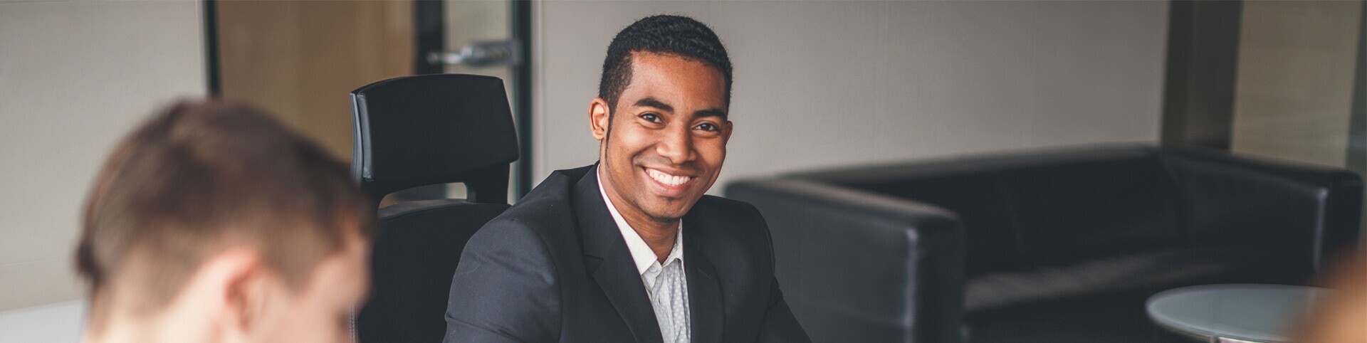 Man smiling among peers in conference room