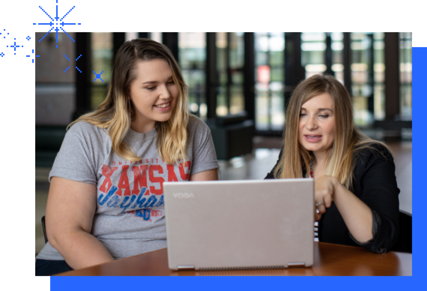 Close-up of two female KU students reviewing a laptop in the campus common grounds.
