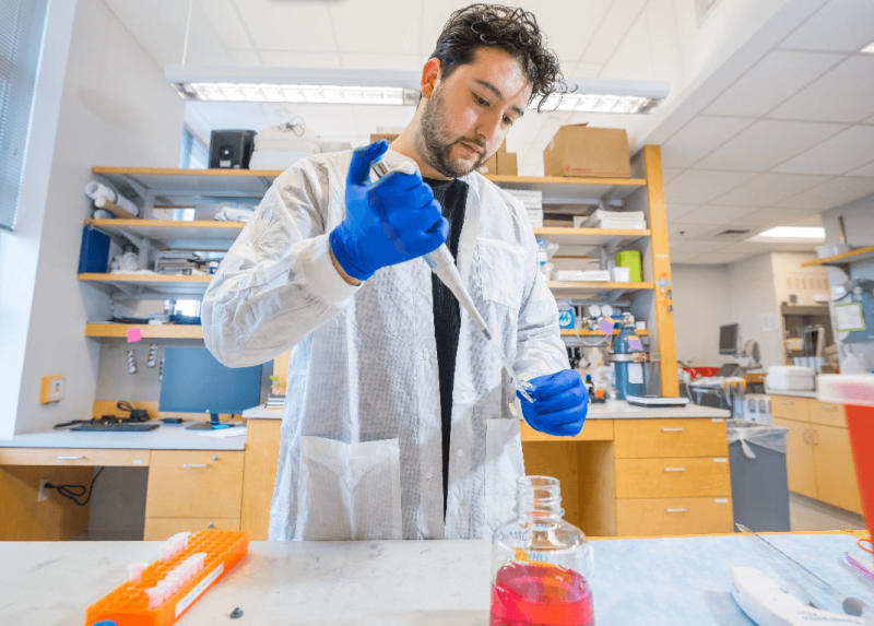 Man in lab coat injecting liquid into test tube