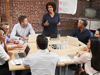 people in a meeting around a table with laptops