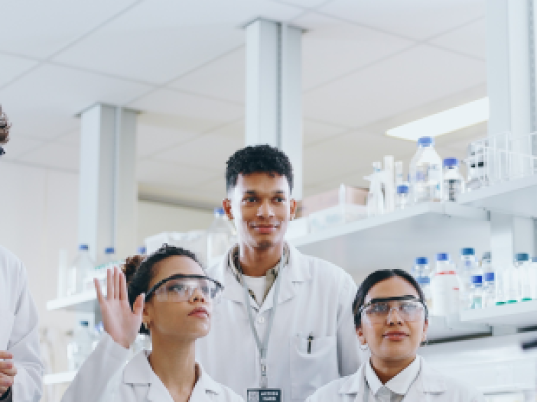 A diverse group of clinical researchers in lab listening during a discussion