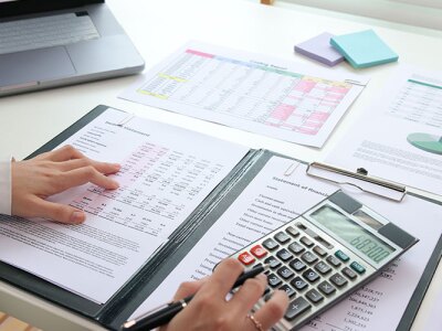 A woman using a calculator while looking at numbers on a piece of paper.