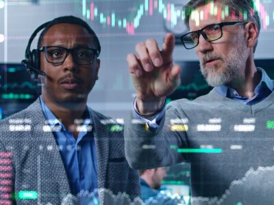 Multiracial financial analysts look on computer generated virtual 3D real-time finance analytics on glass wall.