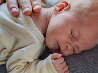 An infant sleeps peacefully on the chest of a bearded man.