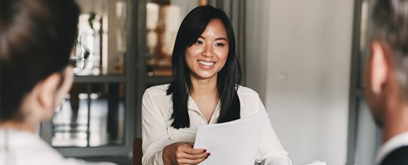woman in white shirt smiling handing paper to two men