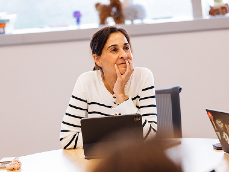 Middle-aged female student sits behind computer while listening to lecture.