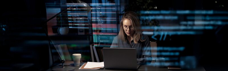 woman sitting at desk in front of laptop displaying security interface
