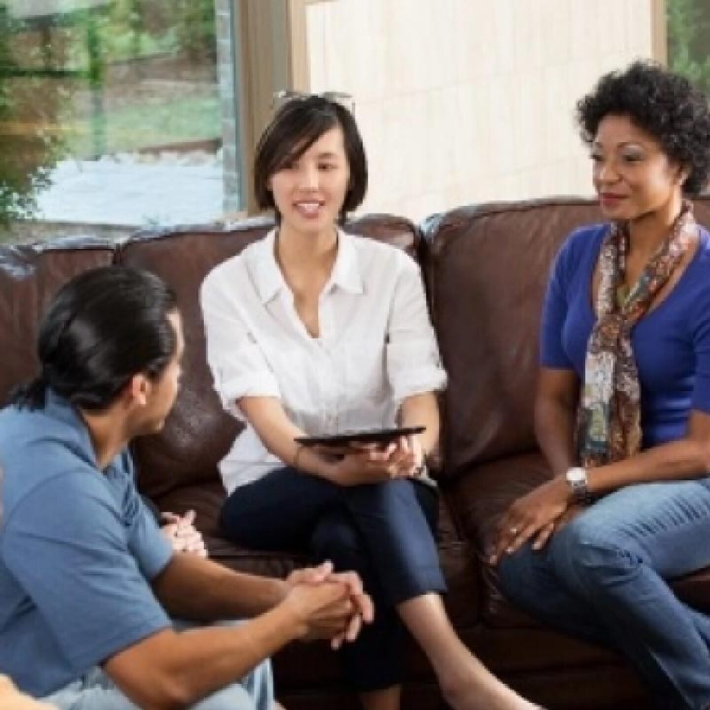 A female social work counselor sits on a couch while listening to a young man.