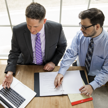 two men in suits working together with a binder