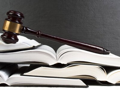 A gavel is on top of a pile of open books.