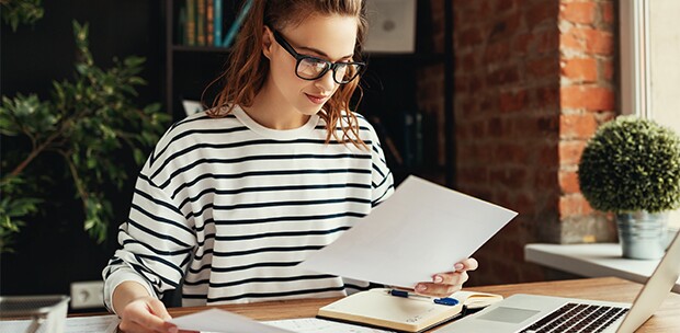 woman-in-black-and-white-stripe-sweater-works-on-resume-for-business-school