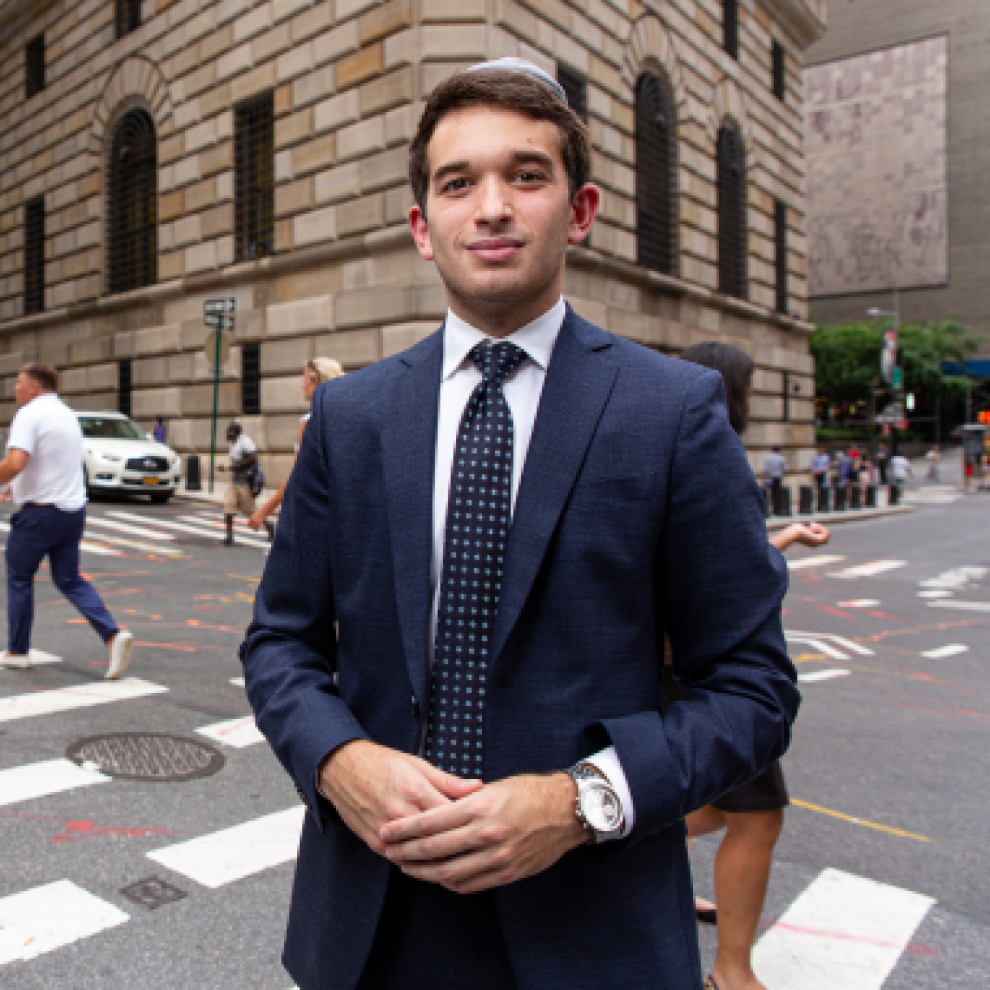 A male Yeshiva University student standing in a New York City crosswalk.