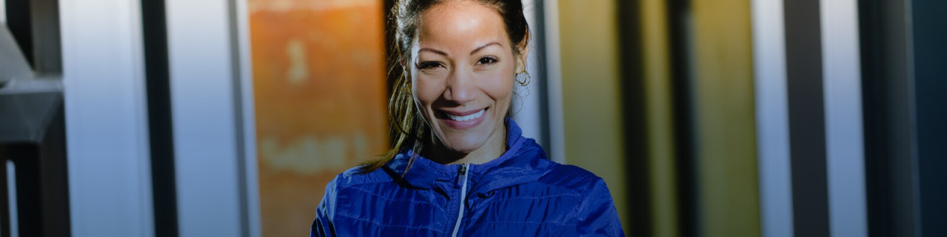 Woman with arms crossed smiling in a blue coat