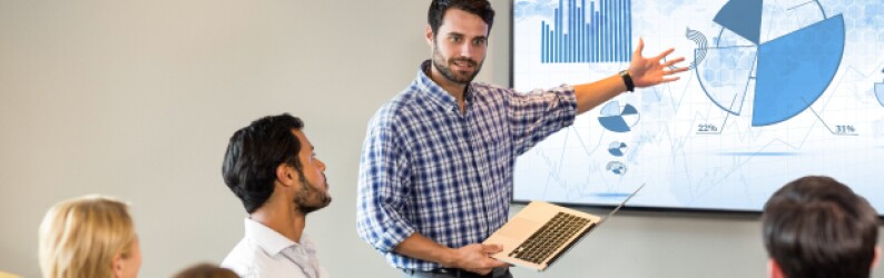 man in plaid shirt presenting pie chart to group