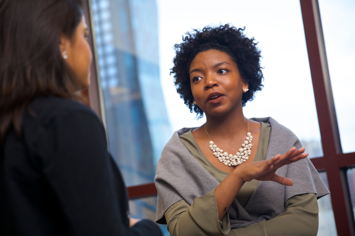 Two women in discussion with a tall building in the background
