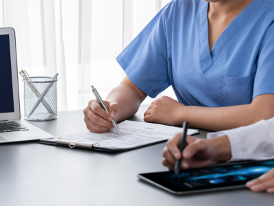 Health care professionals seated at a table, taking notes in front of a "compliance" screen.