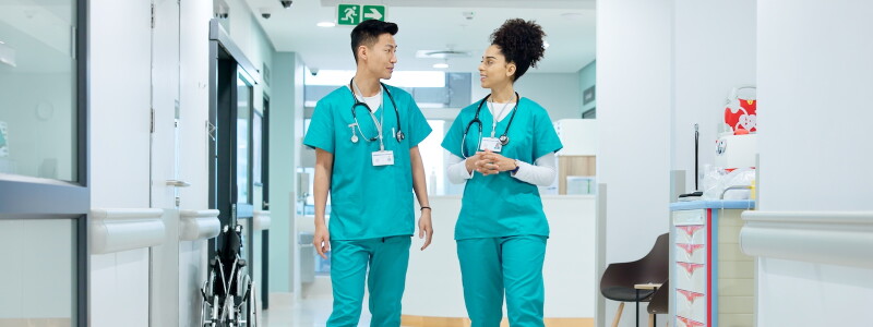 Two nurses discussing patient care in a hospital corridor.