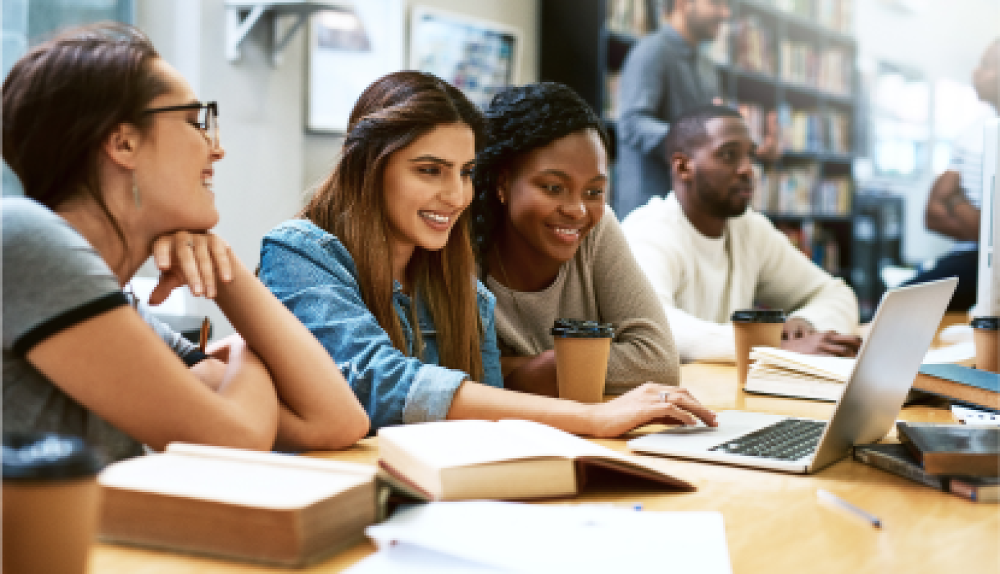 A group of female CWRU students gather in the campus library to review lesson notes.