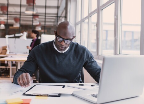 Man working at desk with documents and computer