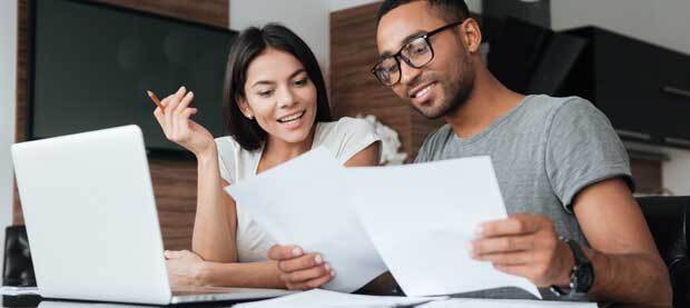 Two graduate students discussing information on paper and on a laptop screen