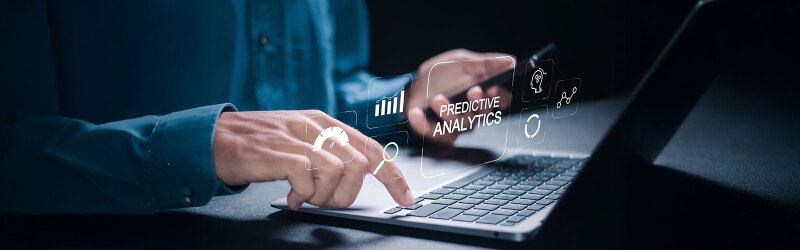 person holding cell phone and typing on laptop displaying predictive analytics icons