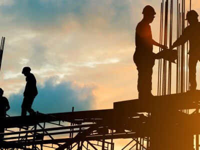 Silhouette of engineer and construction team working at site over blurred background sunset.