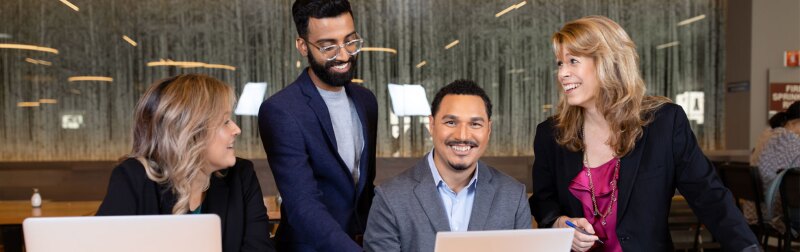 Colleagues gather around a smiling marketer while discussing marketing strategies.
