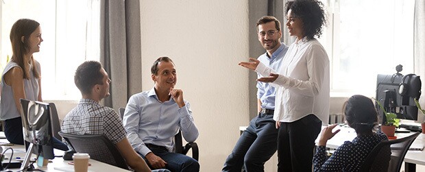 Smiling Black woman speaking at diverse corporate group meeting