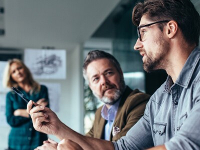 Man talks in meeting with three coworkers
