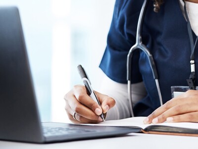 A nursing student studying, surrounded by books and a laptop