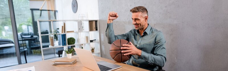Cheerful sports agent holding a basketball while encouraging a client in a meeting.