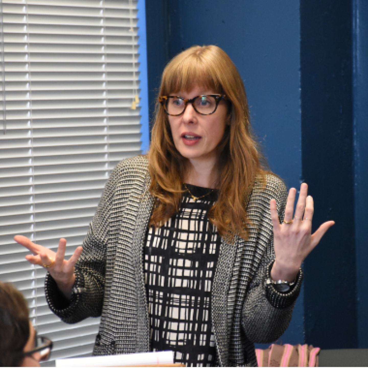 A close-up of a female Yeshiva University professor addressing the class with her arms up.
