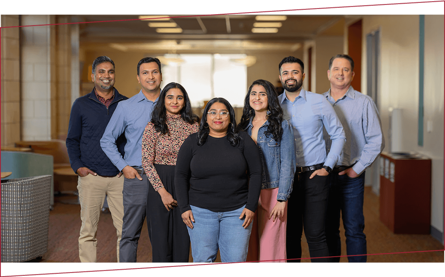 Diverse group of smiling Santa Clara students standing in a building on campus