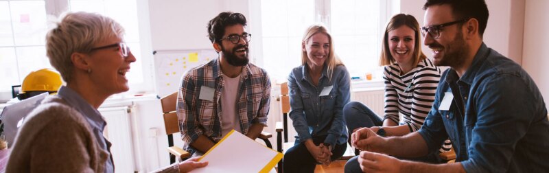 Female social worker sits with a group of volunteers to discuss ethical topics of social work.