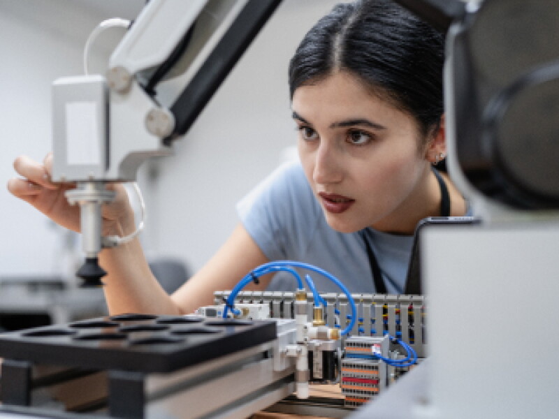 Close-up of a female CWRU student adjusting a machine instrument.