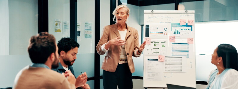 A business professional presents data and charts to colleagues during a strategy meeting.