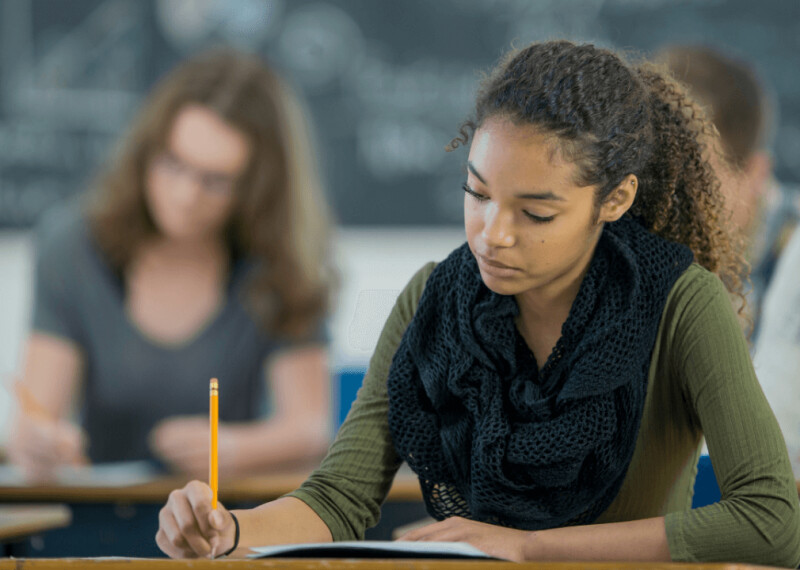 Female student in green sweater and scarf taking GMAT exam