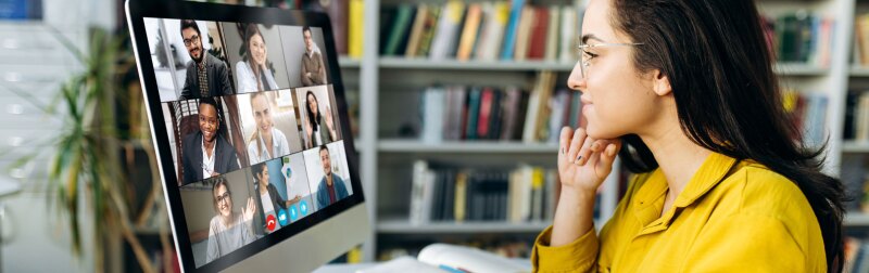 A female student learning online at home, focused watching a computer monitor.