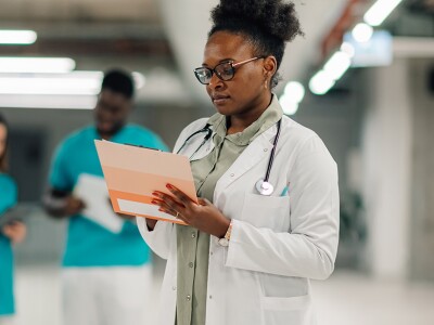 Female doctor reviewing medical documents in hospital corridor